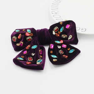 Gros plan détaillé sur une barrette nœud en velours violet foncé sertie de strass