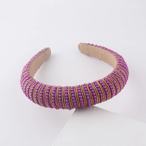 Detail of purple faux pearls and gold beads woven on a sponge headband with soft velvet lining