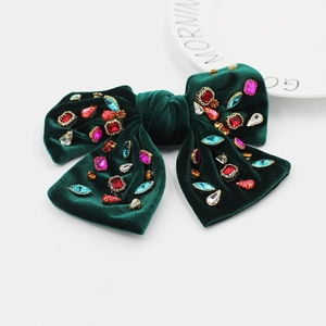 Gros plan détaillé sur la barrette nœud en velours vert foncé avec strass multicolores