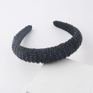 Detail of a thick black padded headband covered in faceted crystals on white props