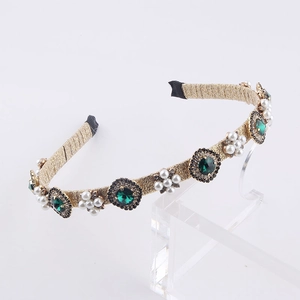 Detail view of gold wire headband with emerald rhinestones and white faux pearl clusters