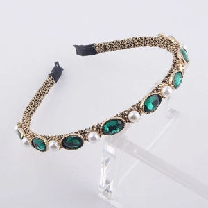 Detailed macro view of vintage gold headband with green gems and white pearls