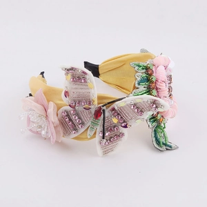Détail de serre-tête papillon perlé avec paillettes et fleurs en mousseline rose sur jaune