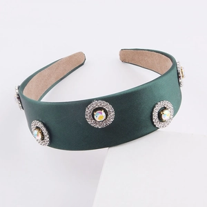 Detail of dark green fabric headband with crystal rhinestones on a white display stand