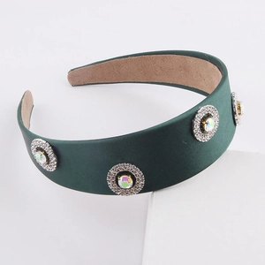 Detail of dark green satin headband featuring sparkling rhinestone and crystal embellishments