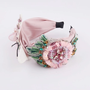Détail d'un serre-tête en velours rose avec fleurs en paillettes et strass brillants