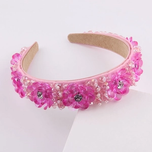 Détail du serre-tête fleurs en cristal rose avec strass et perles sur fond blanc