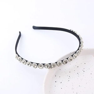 Serre-tête tendance en velours noir orné de strass brillants sur un plat en céramique