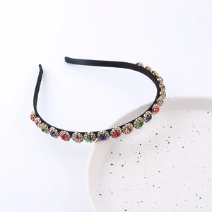 Détail du serre-tête fleurs en cristal coloré avec strass sur une assiette blanche