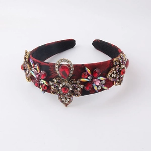 Détail du serre-tête baroque avec strass rouges et fleurs en métal doré sur tissu brodé