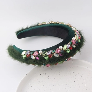 Détail d'un serre-tête en velours vert émeraude avec strass colorés et perles sur assiette