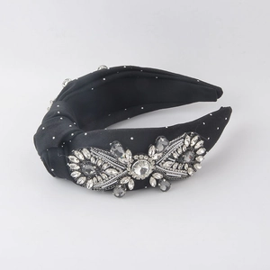 Close-up of elegant black satin knotted headband with crystal flower and silver beading