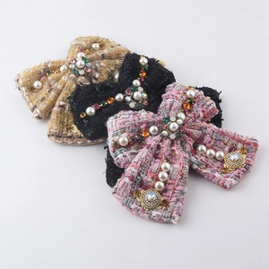 Close-up of tweed bow hair accessories with pearls and colorful rhinestones in three colors