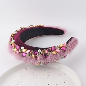 Détail d'un serre-tête en velours bordeaux avec fourrure rose, perles et gemmes