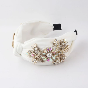 Details des weißen Knotenstirnbands mit künstlichen Perlen, Strass und Blumen-Pailletten
