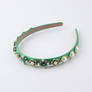 Detailed macro of green satin headband with emerald gemstones and vintage gold floral details
