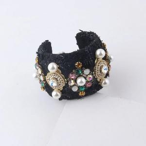 Detail of a black tweed cuff bracelet with pearls, rhinestones and colorful gemstones