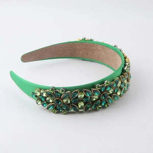Detail view of green baroque headband with intricate crystal flower patterns and emerald gems