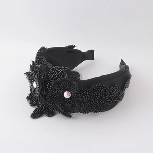 Détail d'un serre-tête en tissu noir avec perles faites à la main et strass colorés AB