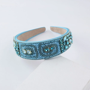 Baroque wide headband with blue beads and rhinestones on a geometric display