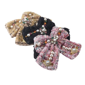 Three tweed bow hair clips with pearls and rhinestones in beige, black, and pink