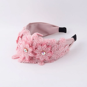 Détail des fleurs en perles faites main et des strass sur le bandeau en tissu rose