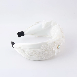 Détail d'un serre-tête blanc perlé avec strass irisés et finition en satin élégant