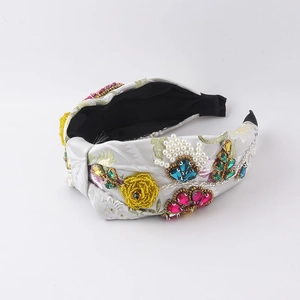 Dettaglio di cerchietto jacquard floreale con perline cucite a mano e strass colorati