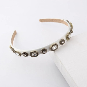 Elegant white padded headband with sparkling crystal embellishments on stone base