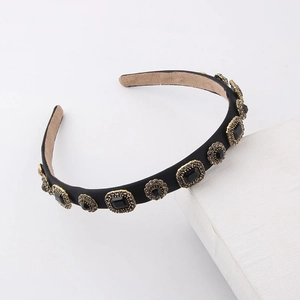 Detail shot of black satin headband featuring gold-rimmed black faceted gemstones decor