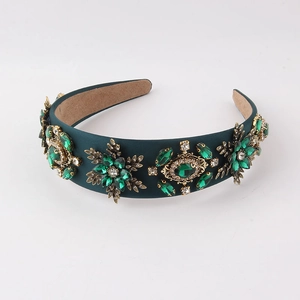 Close-up of baroque emerald green headband with golden floral gem and crystal details