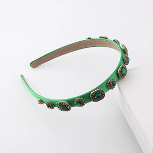 Detailed view of vintage green satin headband with emerald gemstones and golden frame