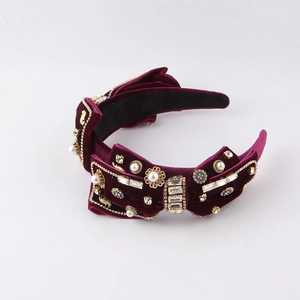 Detail of burgundy velvet headband featuring luxury crystal bow and faux pearls