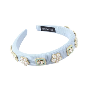 Blue padded headband with pearl flowers and crystal details on a white background