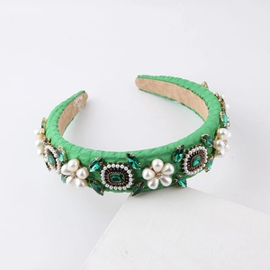 Baroque green sponge headband with pearls and rhinestones on a white display stand