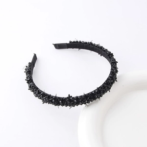 Detail shot of a black braided headband with shimmering crystal beads and sequins on a white base