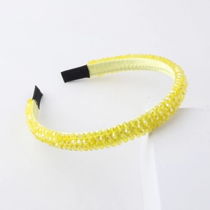 Macro detail of vibrant yellow crystal beads handwoven on a satin headband surface