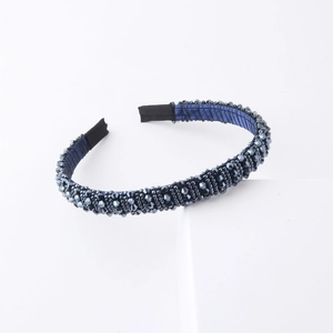 Dettaglio di un cerchietto blu navy con perline sfaccettate su una base rivestita in raso