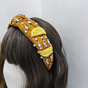 Détail d'un serre-tête noué jaune orné de perles et de motifs citrons sur un modèle