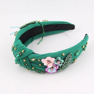 Gros plan du serre-tête vert forêt orné de fleurs en paillettes et de strass émeraude fins