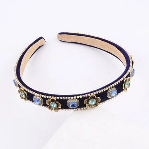French vintage dark blue velvet headband with gold metal flowers and crystals on a white stand