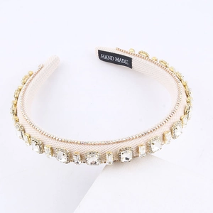 Detail view of rhinestone headband with white fabric and black handmade logo label