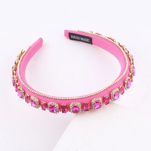 Detailed macro view of pink fabric headband featuring hand-sewn crystals and handmade label