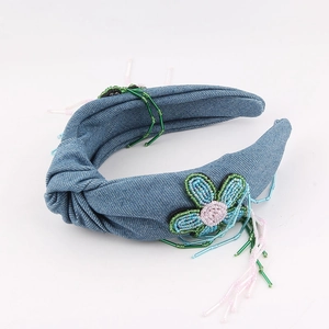 Détail du serre-tête en denim bleu avec motifs floraux perlés et glands colorés