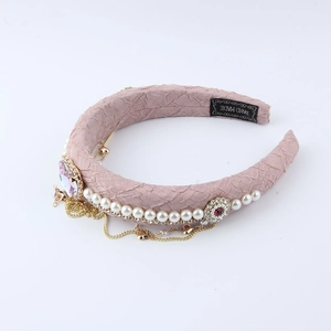 Detail of pink sponge headband with baroque pearls, rhinestones, and heart tassels