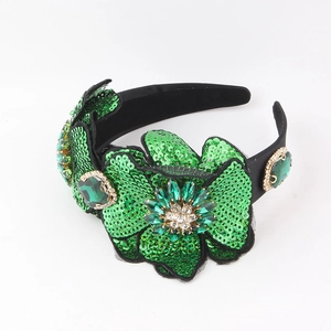 Detail of baroque headband with green sequins and large faceted crystal emerald stones