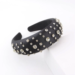 Detail of a padded black headband with multi-size rhinestones on a minimalist stand
