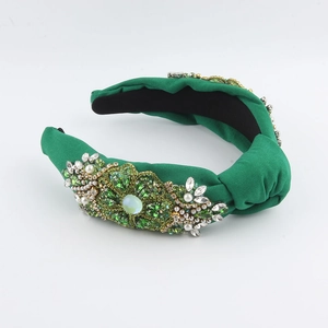 Detailed view of emerald green satin headband with intricate jewel and pearl floral embroidery