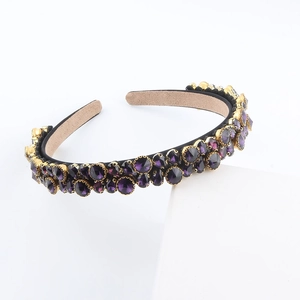 Elegant black headband with deep purple crystals and gold settings on a white stand