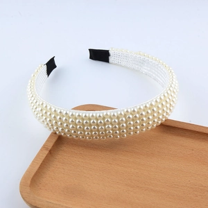 Détail d'un bandeau tressé élégant avec plusieurs rangées de perles blanches sur plateau